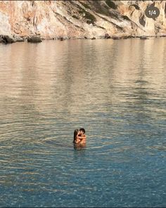 a person swimming in the water near some cliffs