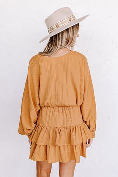 A vision in golden honey, our 'Slight Change Of Plans Dress' features lightweight material with subtle ribbed texturing, a v-cut neckline, long loose sleeves with button closure cuffs, a wide smocked waistline, and a relaxed tiered skirt silhouette that falls into a straight mid-thigh length hemline! Measurements S : Bust 38", Hip 36", Length 34", Sleeve Length 25.5", Waist 24-30". M : Bust 40", Hip 38", Length 34.5", Sleeve Length 26", Waist 26-32". L : Bust 42", Hip 40", Length 35", Sleeve Len Casual Long Sleeve Dress With Crinkle Texture, Long Sleeve Dress With Crinkle Texture For Spring, Long Sleeve Crinkle Texture Dress For Spring, Golden Honey, Loose Sleeves, S B, V Cut, V Cuts, Tiered Skirt