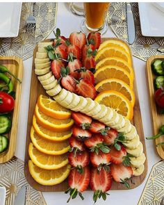 sliced fruit and vegetables arranged on serving trays next to beer glasses, forks and utensils