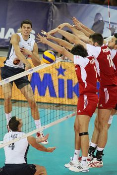 the men are playing volleyball on the court