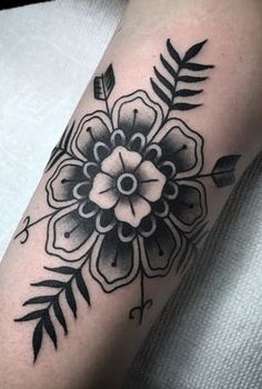 a black and white flower with leaves on the arm, done by tattoo artist person