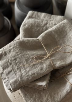 four linen napkins tied with twine and sitting on a table next to pots