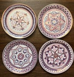 four purple and white plates sitting on top of a wooden table