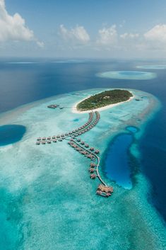 an island in the middle of the ocean surrounded by blue water and small huts on it