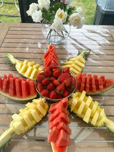 fruit arranged in the shape of a star on a table with flowers and watermelon