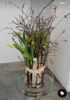 a glass vase filled with lots of branches and flowers on top of a cement floor