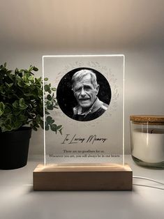 a glass plaque with an image of a man on it next to a potted plant