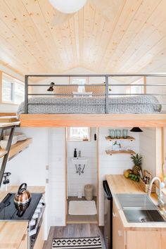 the interior of a tiny house with wood flooring and white walls, including stairs