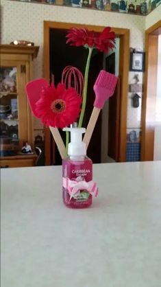 pink flowers in a vase with toothbrushes and hairdryer on the counter