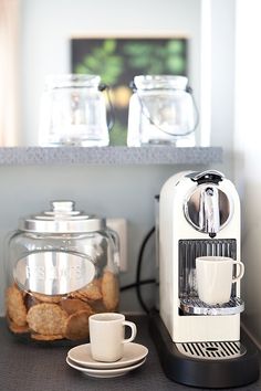 a coffee maker sitting on top of a counter next to a cup and saucer