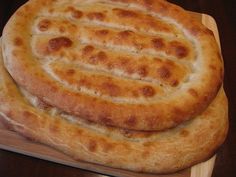 two large round breads sitting on top of a cutting board next to each other