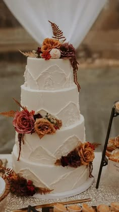 a three tiered wedding cake sitting on top of a table next to donuts