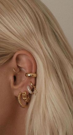 a woman with blonde hair wearing three different types of ear piercings