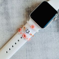 an apple watch is decorated with beaded flowers and a smiley face on the strap