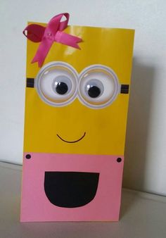 a yellow and pink paper bag with eyes and a bow on the top that is shaped like a minion