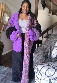 a woman standing in a living room holding a purple scarf