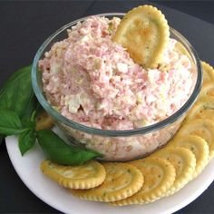 a plate with crackers and a bowl filled with tuna salad next to sliced lemons