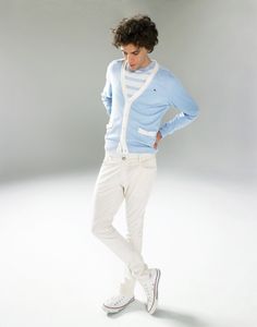 a young man in white pants and a blue sweater