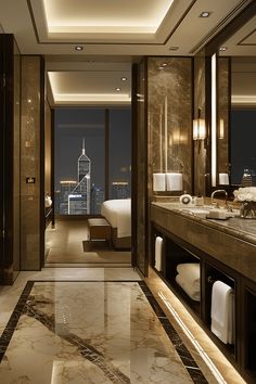 a bathroom with marble flooring and large windows overlooking the city at night, in an upscale hotel