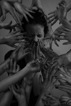 a woman surrounded by many hands reaching up to her face