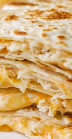 a stack of quesadillas sitting on top of a white plate covered in cheese