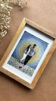 a framed photo of two people standing next to each other on a table with flowers in the background