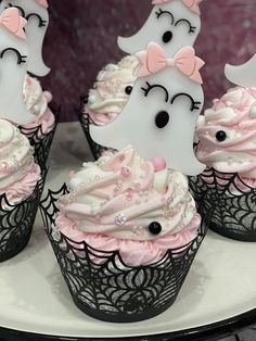 cupcakes decorated with white frosting and pink icing are sitting on a plate