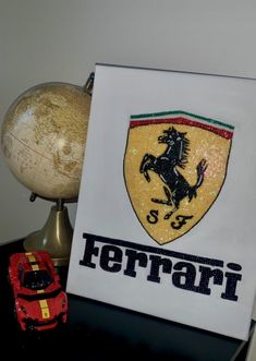 there is a ferrari sign on the table next to a toy car and a globe