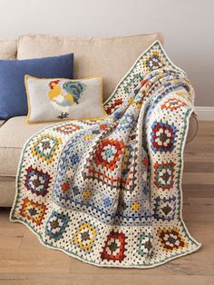 a couch with a crocheted blanket on top of it next to a pillow