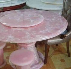 the table is covered in pink marble and has three matching chairs around it, along with plates on top