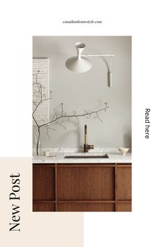 a kitchen with white walls and wood cabinetry in the center, an overhead light fixture hangs over the sink