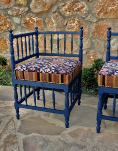 two blue chairs sitting next to each other in front of a stone wall