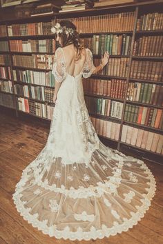 a woman standing in front of a bookshelf wearing a white dress and veil