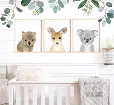 three pictures of animals hanging on the wall in a baby's room with greenery