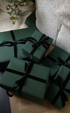 several wrapped presents sitting on a table next to a christmas tree