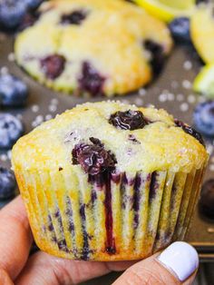 a person holding a muffin with blueberries and lemons