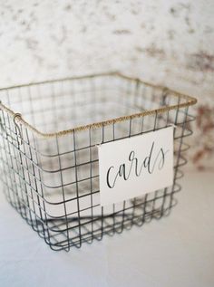 a wire basket with a sign that says cards on it sitting on a white surface