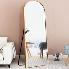 a large mirror sitting on top of a floor next to a white couch