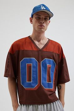 Mesh football jersey by Urban Outfitters. Semi sheer short sleeve t-shirt with a number graphic at the front. Boxy fit tee in a cropped length. Features UO football v-neck jersey Mesh football jersey tee Two-tone V-neck Short sleeve Number graphic Sheer mesh Short sleeve Boxy fit Cropped length Content + Care 100% Polyester Machine wash Imported Size + Fit Model in Green is 6’2.5" and wearing size Medium Measurements taken from size Medium Chest: 46" Length: 23.5" | Urban Outfitters UO Mesh Foot Varsity Style Short Sleeve Graphic Print Top, Cropped Football Jersey, Jersey Tops With Team Logo For Streetwear, Varsity Style Baseball Jersey With Short Sleeves, Collegiate Sports Tops With Number Print, Team Logo Jersey Tops With Short Sleeves, Jersey Tops With Team Logo And Short Sleeves, Football Season Sports Fan T-shirt For Streetwear, Team-colored Short Sleeve Baseball Jersey For Game Day