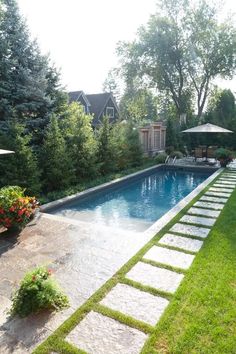 a backyard with a swimming pool surrounded by greenery