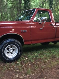 a red pick up truck parked in the woods