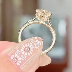 a woman's hand holding a ring with flowers on it