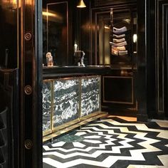 a bathroom with black and white tile flooring and gold trim around the sink area