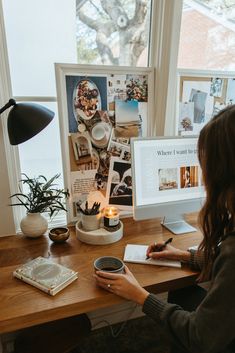 a woman sitting at a desk writing on a piece of paper in front of a computer