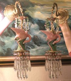 two pink flamingos are hanging from chandeliers