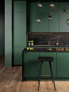 a green kitchen with marble counter tops and stools in front of the bar area