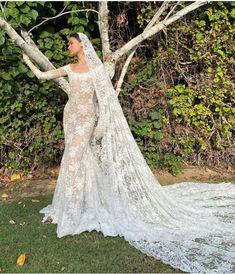 a woman in a wedding dress standing next to a tree