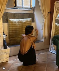 a woman sitting on the floor in front of a window