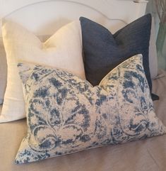 two blue and white pillows sitting on top of a bed