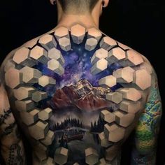 the back of a man's body is covered in geometric designs and he has tattoos on